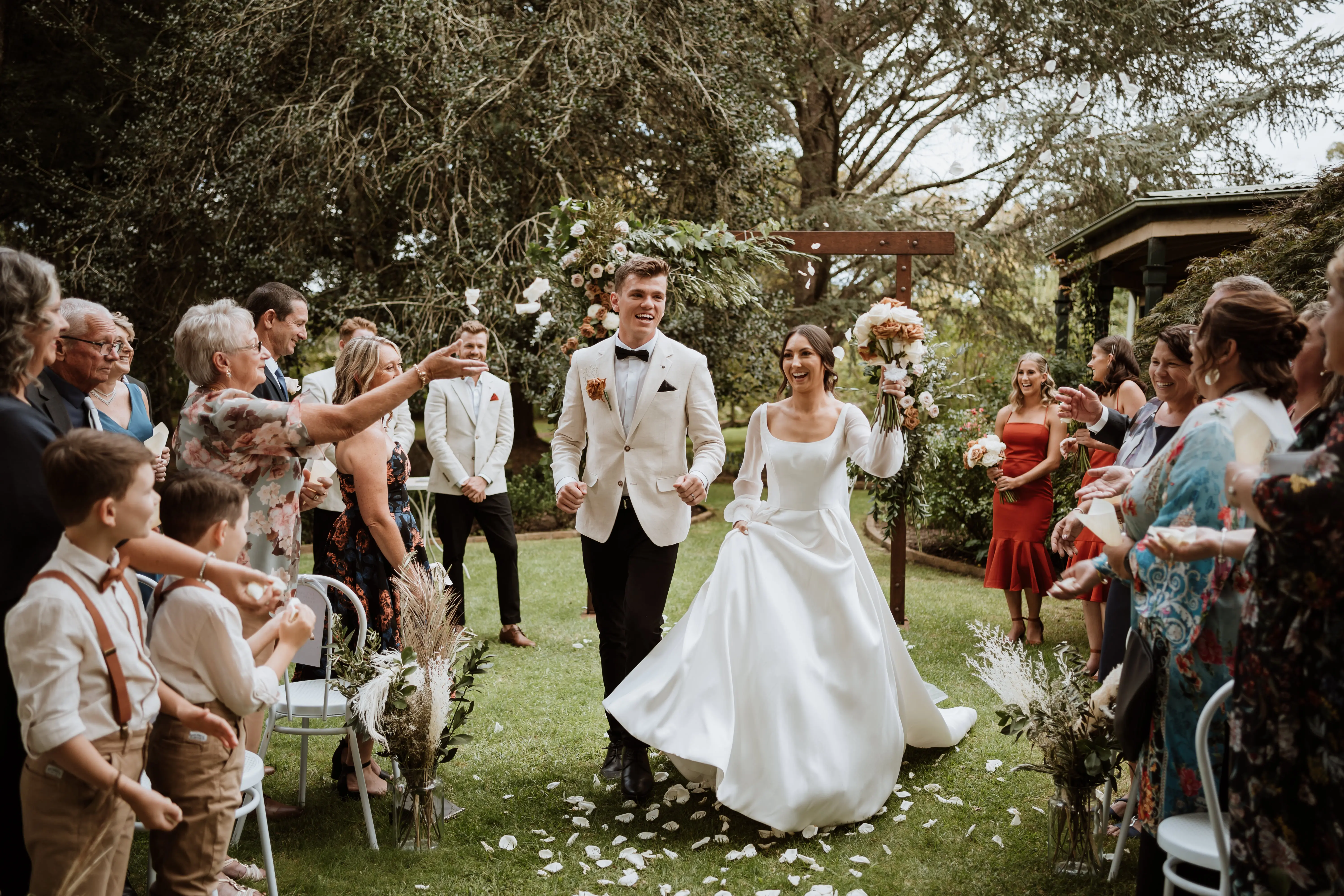 Bride wearing Selena satin wedding dress by Rebecca Ingram exiting her ceremony with her husband.